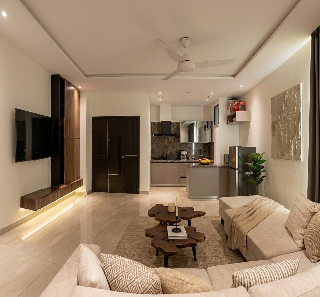 A modern living room with a sofa, coffee table, and a TV mounted on the wall.