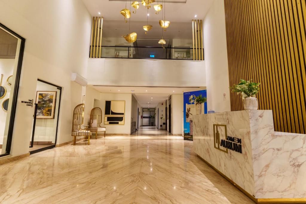 Eine Hotelhalle mit Marmorboden, einer Rezeption und einer Treppe zu einer oberen Ebene.