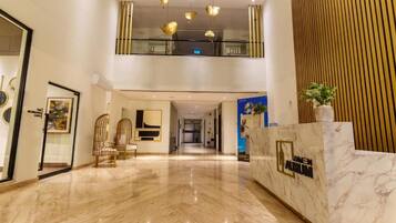 Eine Hotelhalle mit Marmorboden, einer Rezeption und einer Treppe zu einer oberen Ebene.