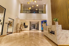 A hotel lobby with a marble floor, a reception desk, and a staircase leading to an upper level. - Aurevia Stays Your Stay in peaceful Lahore with pool, cinema and gym access (Lahore)