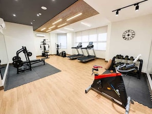 Un gimnasio con cintas de correr, máquinas de pesas y mancuernas.