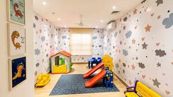Ein Spielzimmer für Kinder mit Rutsche, Spielhaus und Spielzeug.