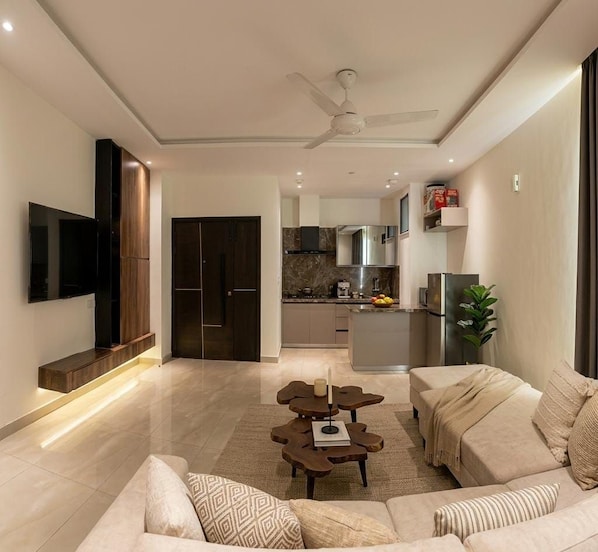 Una sala de estar moderna con un sofá, una mesa de centro y un televisor montado en la pared.
