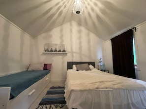 A bedroom with a single bed, a smaller bed, a nightstand, a lamp, a shelf with Eiffel Tower prints, and a chandelier. - 5 Person Holiday Home in Uddevalla (Uddevalla)