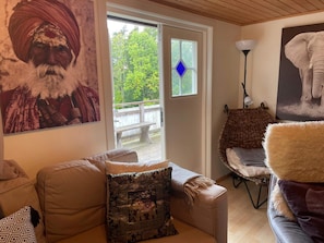 A living room with a sofa, a patterned throw pillow, a wicker chair, a fluffy rug, and a painting of an elephant. - 5 Person Holiday Home in Uddevalla (Uddevalla)