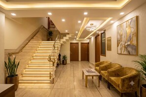 Eine Hotelhalle mit Treppe, Sitzgelegenheit und Rezeption.
