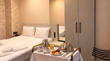 A hotel room with a bed, a breakfast trolley, a wardrobe, and a mirror.