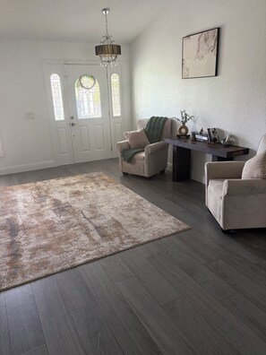 A living room with a large rug, two armchairs, a coffee table, and a chandelier. - Bonita Springs Paradise, Pool spa Canal home 5 min to city 20 min to beach & RSW (Bonita Springs)