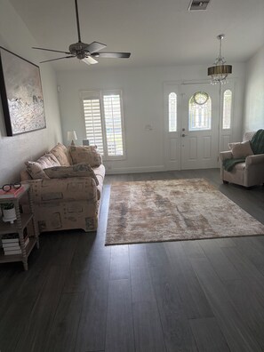 A spacious living room with a large rug, a ceiling fan, and a chandelier. - Bonita Springs Paradise, Pool spa Canal home 5 min to city 20 min to beach & RSW (Bonita Springs)