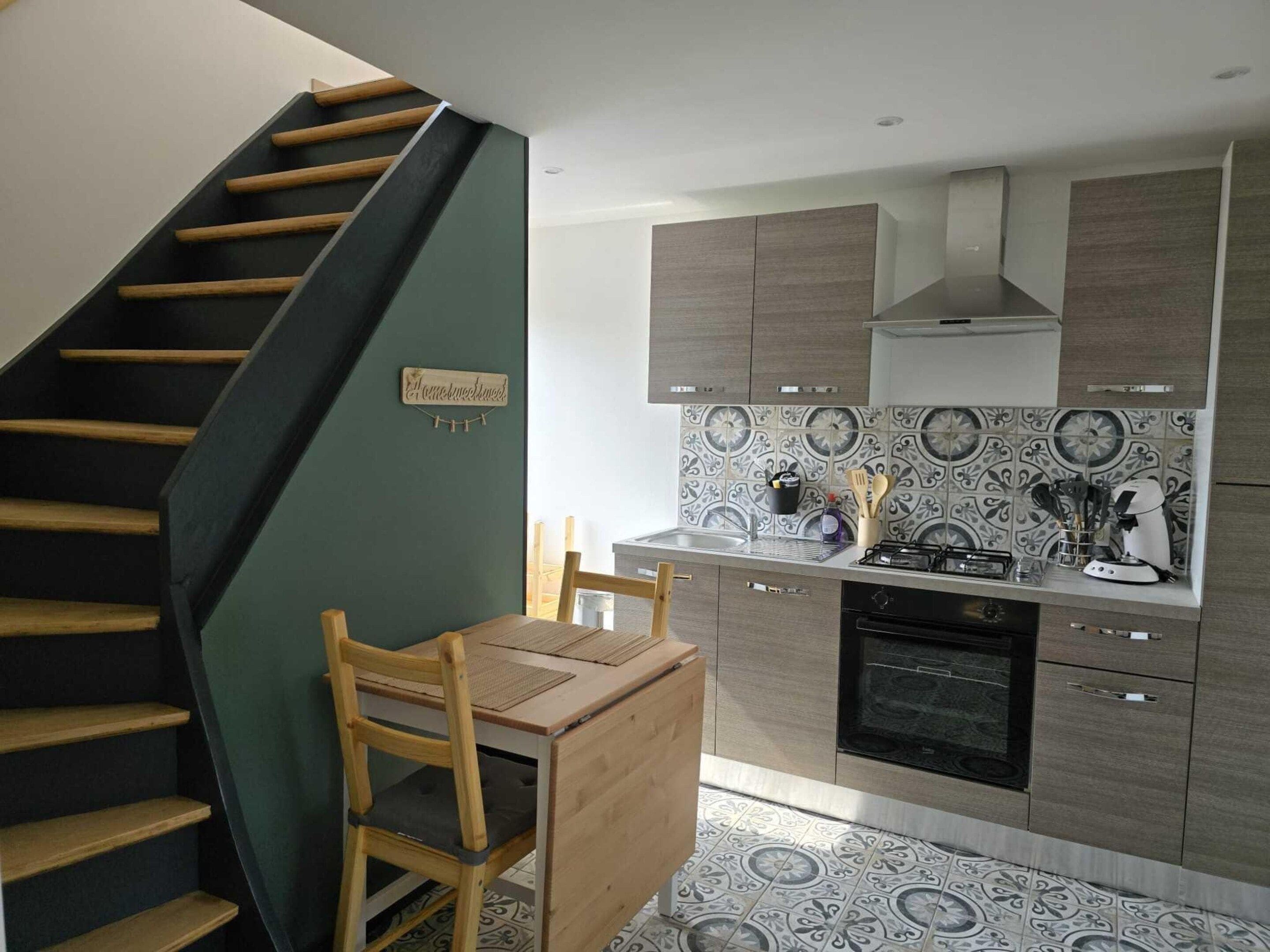 Une cuisine avec un escalier en bois, une table à manger et des placards.
