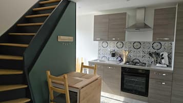 Une cuisine avec un escalier en bois, une table à manger et des placards.