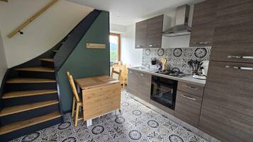Una cocina con una escalera de madera, una mesa de comedor y baldosas de suelo con diseño.