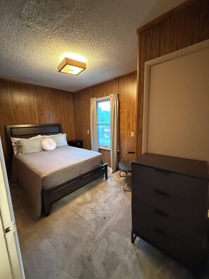 A bedroom with a bed, dresser, and a window with curtains. - "The Office" themed house in charming Topeka (Topeka)