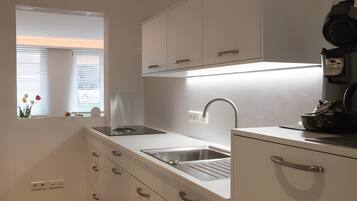 Een moderne keuken met een ingebouwde kookplaat, een roestvrijstalen spoelbak en witte keukenkastjes.