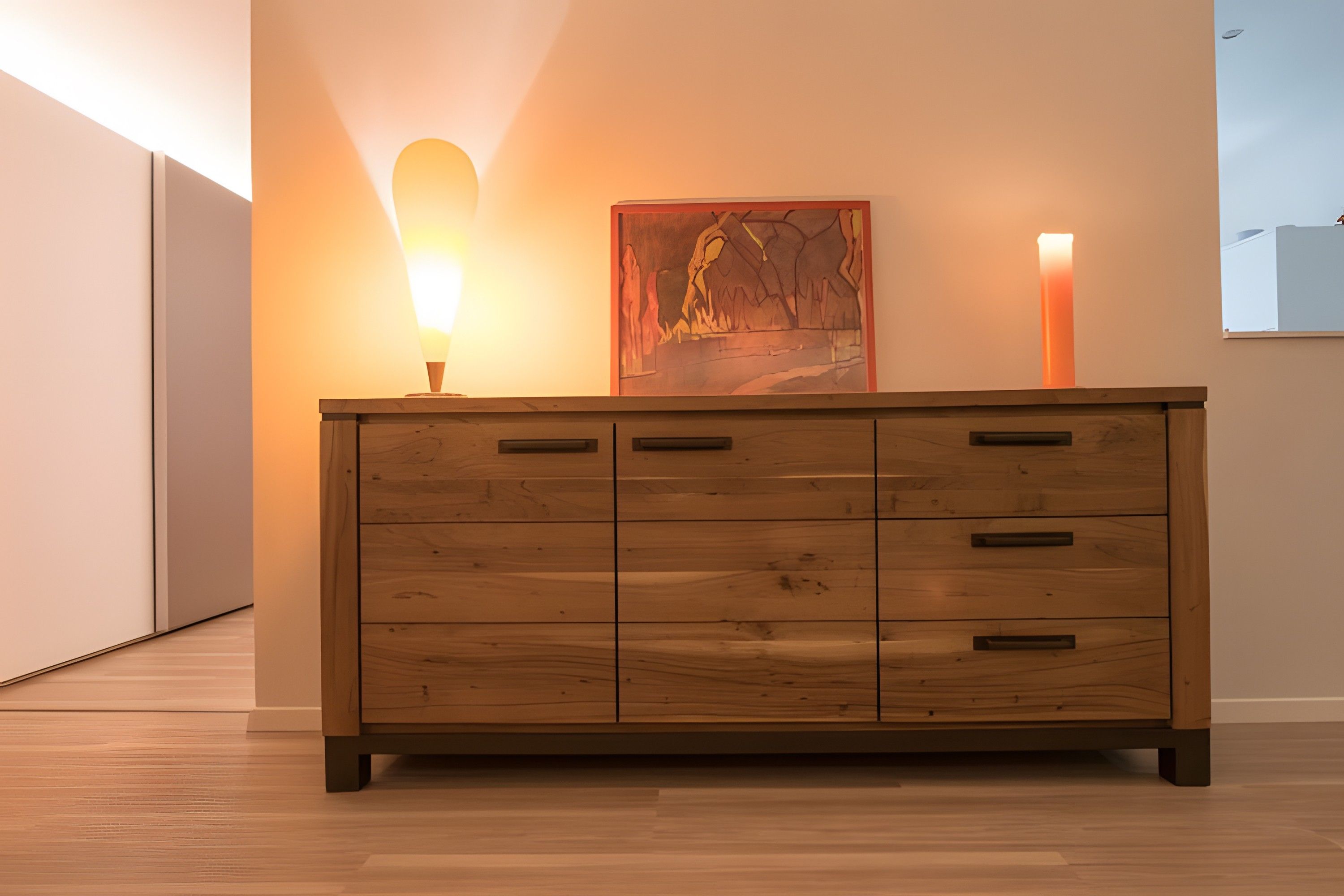Een houten dressoir met meerdere laden, een wandlamp en een schilderij.