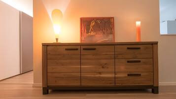 Een houten dressoir met meerdere laden, een wandlamp en een schilderij.