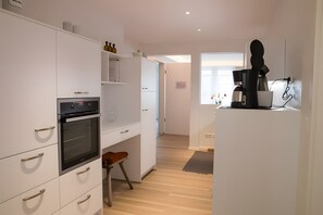 A modern kitchen with white cabinetry, a built-in oven, and a coffee machine. - Apartment 'Großzügiges Ferienapartment' with Shared Garden – Central, Accessible (Kappelrodeck)