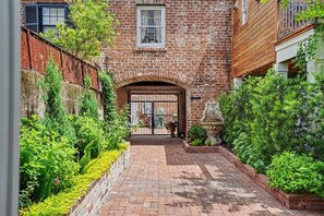 A brick building with a gated entrance, a brick pathway, and lush greenery. - Historic Savannah Estate by Forsyth Park (Savannah)