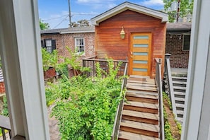A wooden house with a front door, a staircase leading up to it, and a small garden area. - Historic Savannah Estate by Forsyth Park (Savannah)