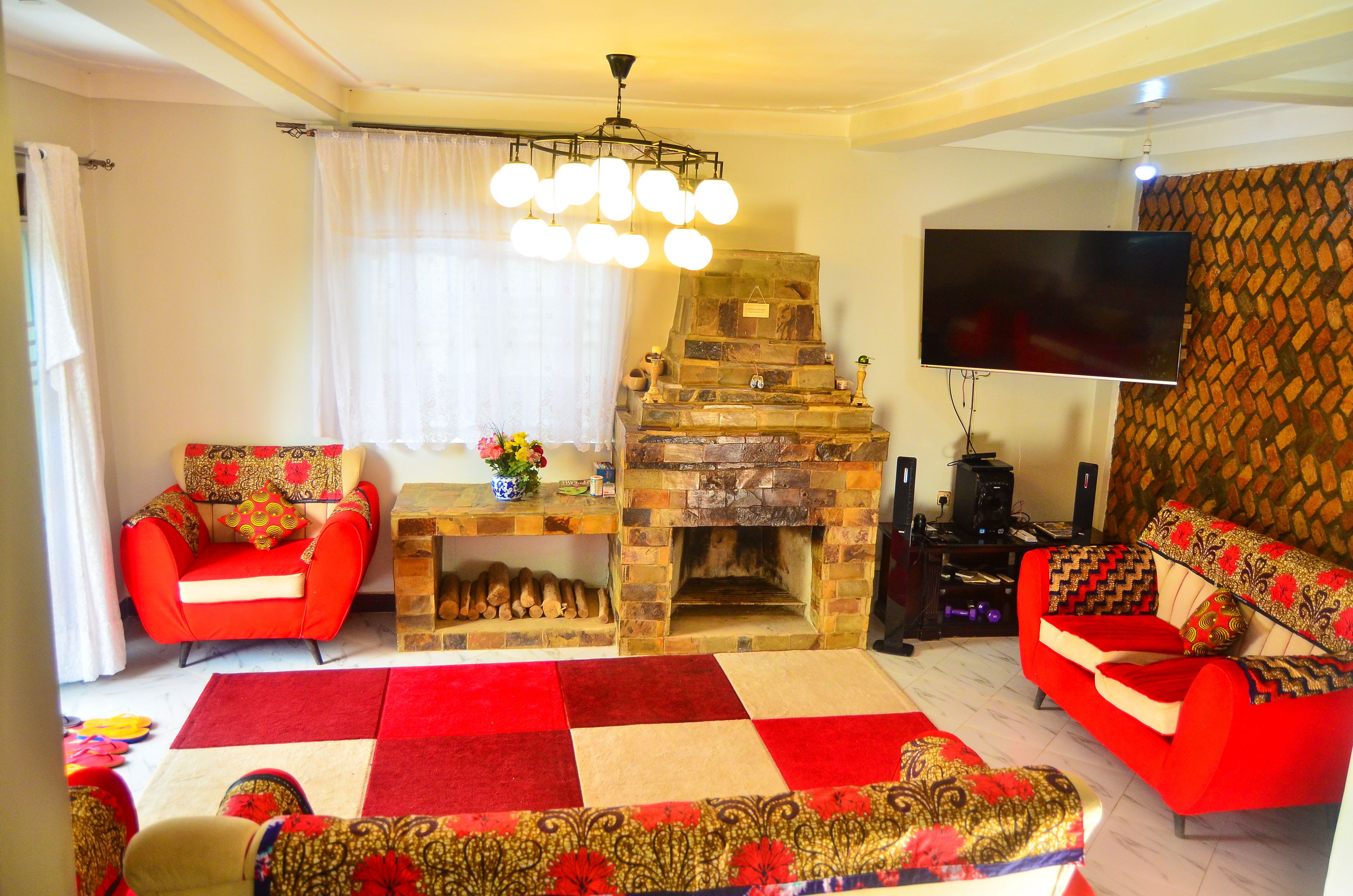 A living room with a fireplace, red sofas, a television, and a patterned rug.
