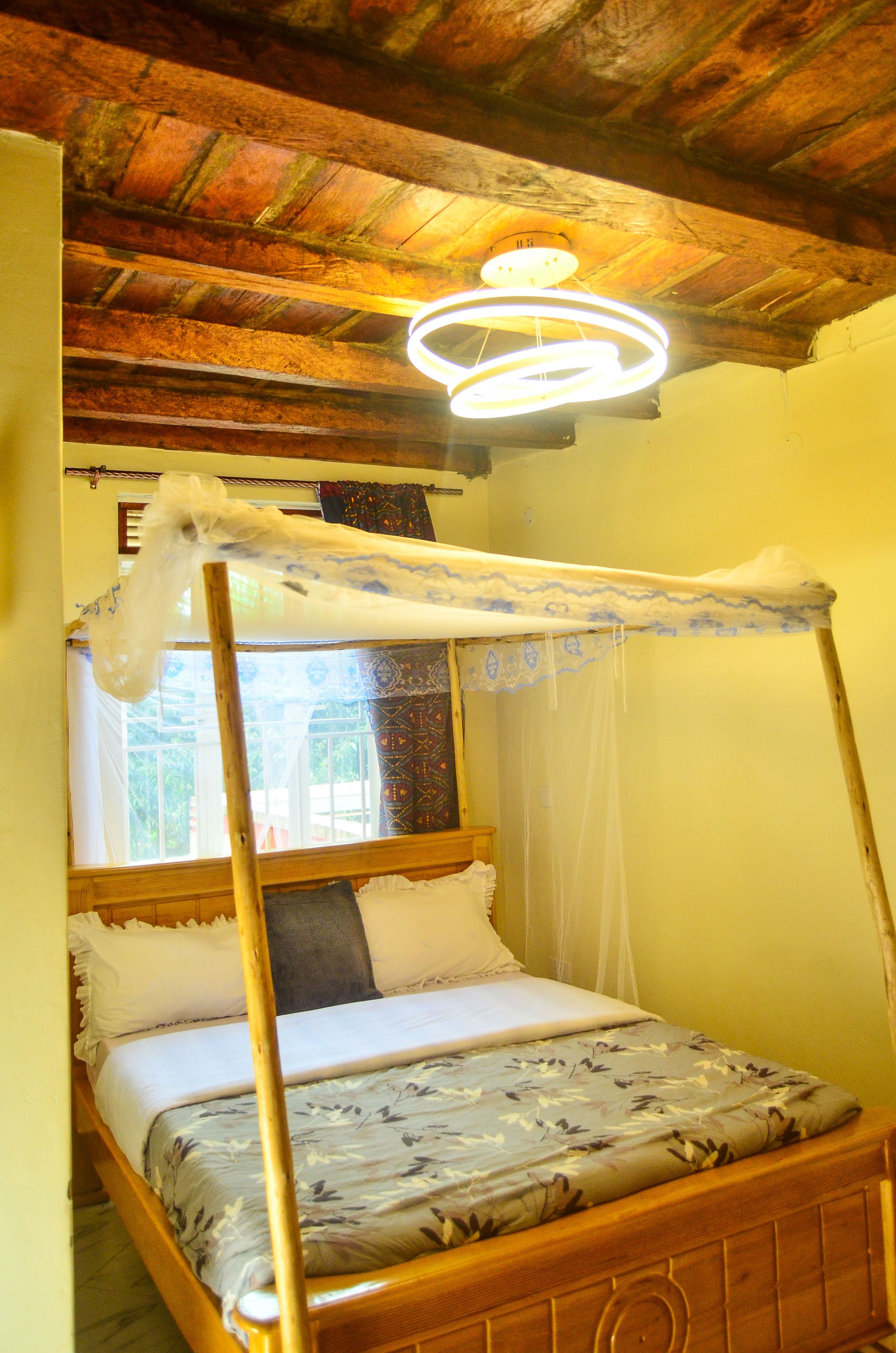 Una cama individual con dosel, cabecera de madera y colcha estampada con motivos florales.