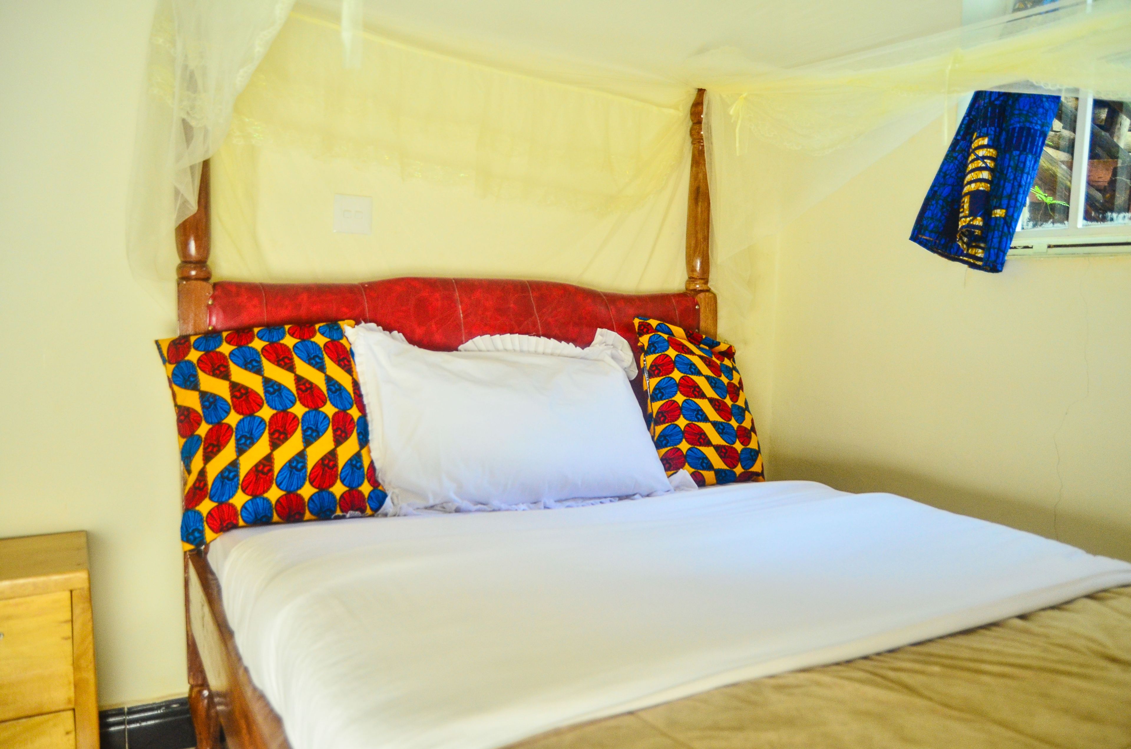 A bed with a canopy, a wooden headboard, and colorful pillows.