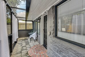 A covered outdoor area with a brick patio, a table with a chair, and a door with a window. - 3 Mi to Dtwn! Cozy Tampa Home Base (Tampa)