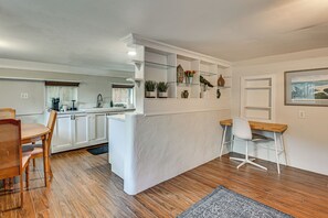 A modern kitchen with white cabinetry, a dining area with a wooden table and chairs, and a small office space with a desk and chair. - 3 Mi to Dtwn! Cozy Tampa Home Base (Tampa)