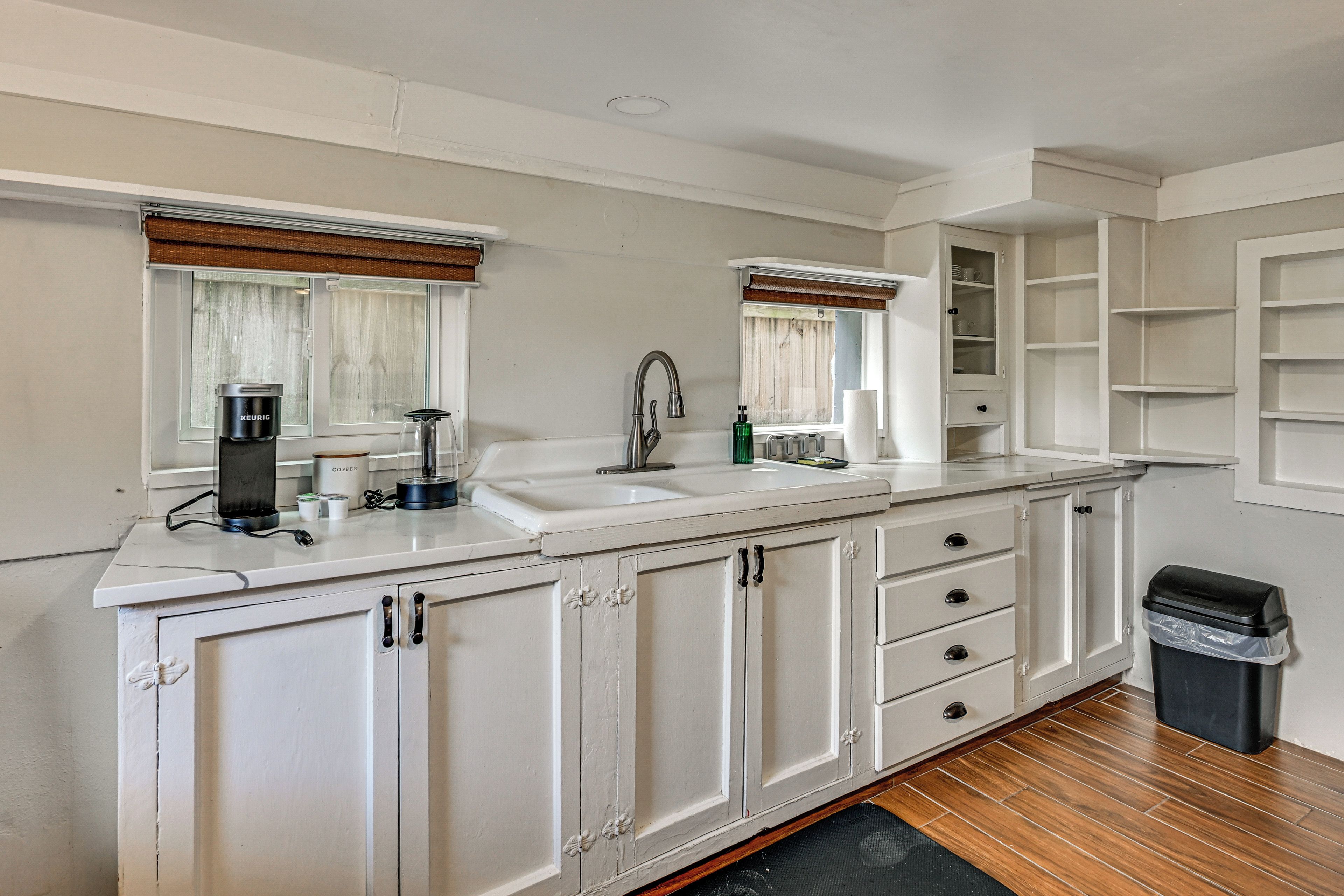 A kitchen with a large sink, a coffee maker, and a cabinet with drawers.
