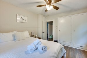 Ein Schlafzimmer mit einem Bett, einem Deckenventilator, einem gerahmten Bild und einem Kleiderschrank.