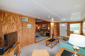 A room with wooden walls, a television, a sofa, a coffee table, and a lamp. - Flip Flop Cottage: Lake Access in Clermont (Clermont)