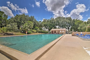 A clear swimming pool with a lifeguard chair, surrounded by trees and a building with a sign. - Flip Flop Cottage: Lake Access in Clermont (Clermont)