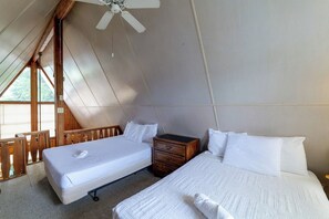A bedroom with two beds, a wooden nightstand, and a ceiling fan. - Flip Flop Cottage: Lake Access in Clermont (Clermont)