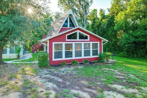 Ein kleines rotes Haus mit einem steilen Dach, umgeben von üppiger Vegetation.