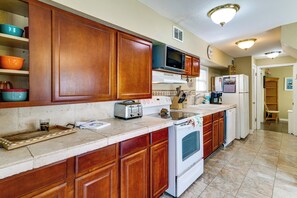 A kitchen with wooden cabinets, a microwave, a toaster, and a refrigerator. - Sun-kissed Cottage: Lake Access, 14 Mi to Disney (Clermont)