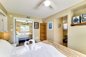 A hotel room with a bed, a ceiling fan, a wooden chair, a wooden shelf, and a wall-mounted speaker. - Sun-kissed Cottage: Lake Access, 14 Mi to Disney (Clermont)