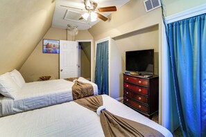 Een slaapkamer met twee bedden, een dressoir, een televisie en een plafondventilator.