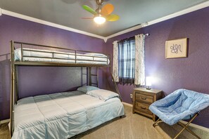 Un lit superposé avec une échelle, une chaise, une table de chevet, une lampe et un ventilateur de plafond.