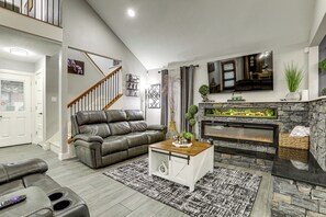A modern living room with a leather sofa, a fireplace, and a mounted TV. - Game Room & Private Yard! Family Houston Escape (Houston)
