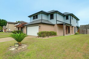 Une maison à deux étages avec un garage, des fondations en briques et une pelouse bien entretenue.
