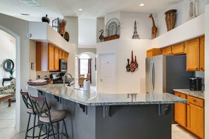 A modern kitchen with granite countertops, wooden cabinets, and stainless steel appliances. - Spacious 4BR w/ South-facing Pool/spa: Disney 11mi (Clermont)