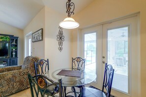 A dining area with a glass table and chairs, a decorative sign on the wall, and a ceiling light fixture. - Spacious 4BR w/ South-facing Pool/spa: Disney 11mi (Clermont)