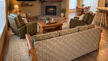 A living room with a fireplace, leather sofas, a coffee table, and a television mounted on the wall.