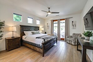Ein Schlafzimmer mit Bett, Nachttischen, Deckenventilator, Fenstern und Blick ins Freie.