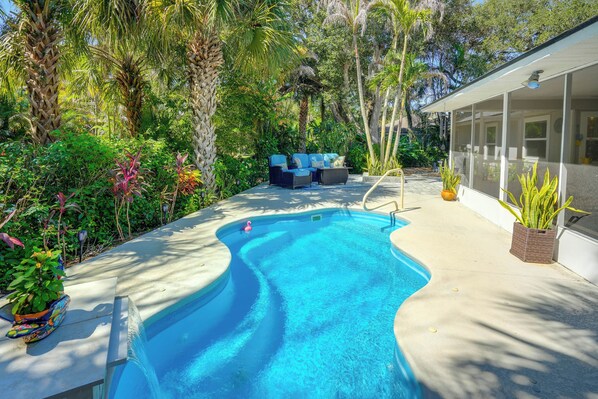 A swimming pool with a wavy edge, surrounded by lush greenery and a covered outdoor seating area. - 4 Minute Walk to Private Beach Plus a Private Pool (Vero Beach)