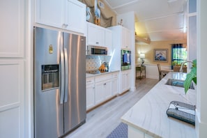 A modern kitchen with stainless steel appliances, white cabinetry, and a marble countertop. - 4 Minute Walk to Private Beach Plus a Private Pool (Vero Beach)