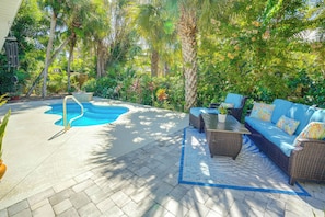 A pool area with a lounge chair and a sofa, surrounded by lush greenery. - 4 Minute Walk to Private Beach Plus a Private Pool (Vero Beach)