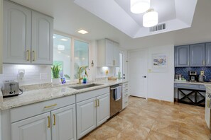A modern kitchen with white cabinetry, a granite countertop, and a built-in dishwasher. - Walk to Wigwam Resort! Family & Golfers Oasis (Litchfield Park)