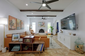 Una sala de estar moderna con un sofá, una mesa de centro, un televisor y un ventilador de techo.