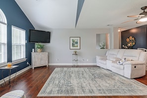 A living room with a large flat-screen TV, a sofa, a coffee table, and a patterned rug. - Murrells Inlet Condo: Close to Beaches, Amenities (Murrells Inlet)